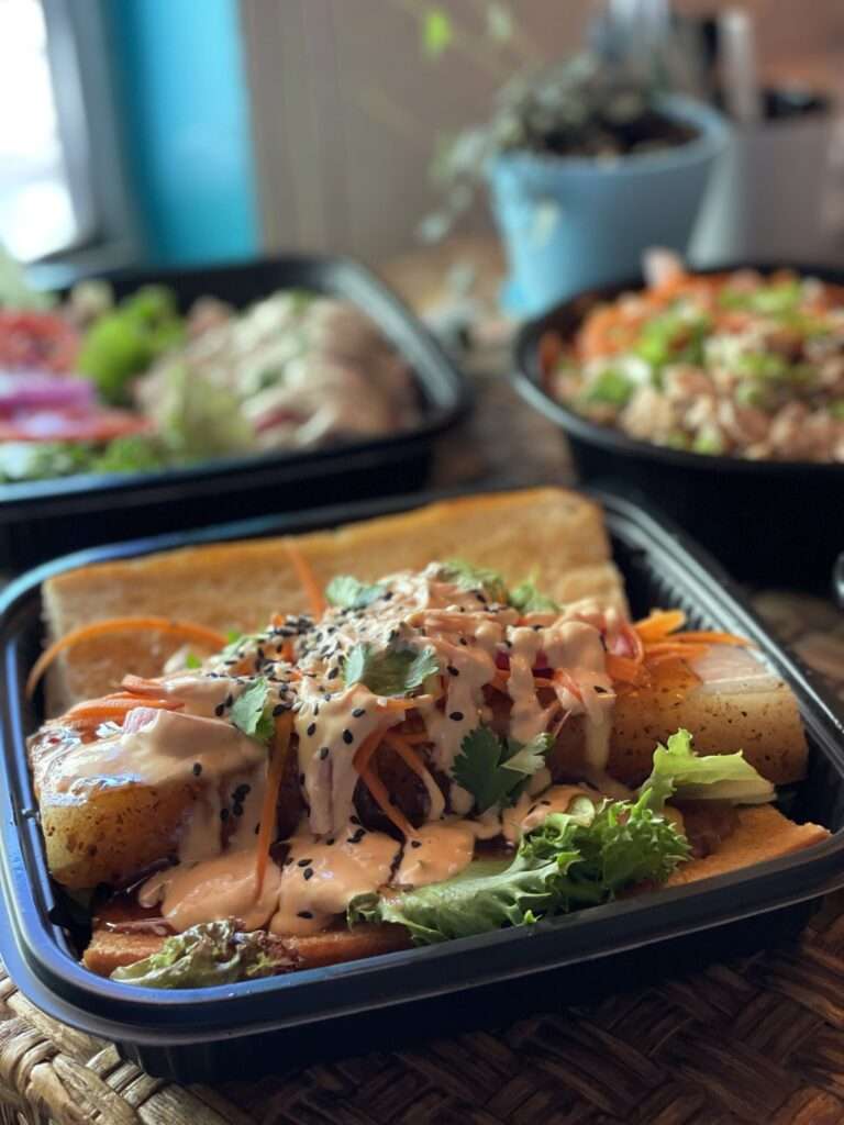 A photo of a black plastic tray of Mexican food with other dishes in the background.