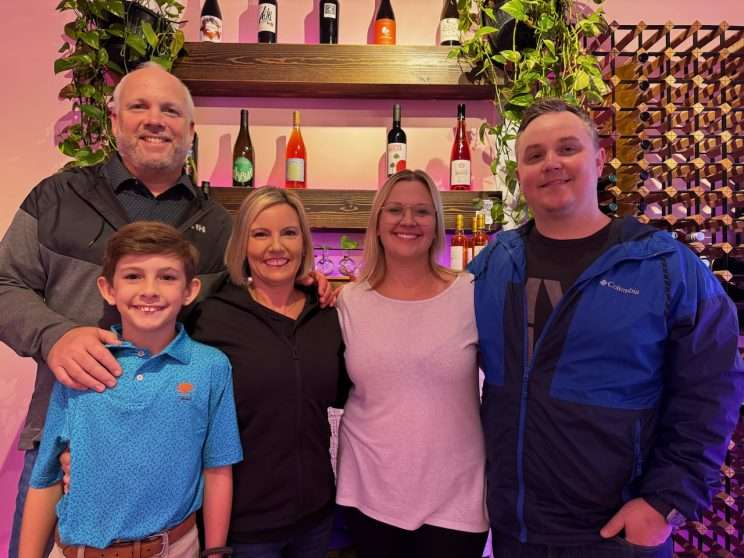 Four people and a younger person looking at the camera at Gulfport Wine House