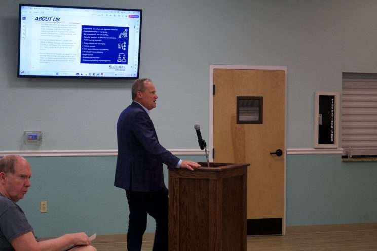 a man standing at a lectern during the Kenneth City lobbyist discussion