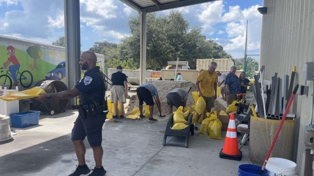 people loading bags with sand from a sand pile and city staff assisting.