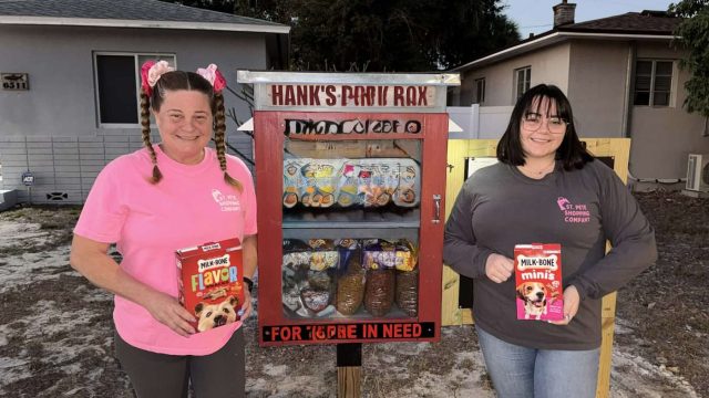 Two women stand in front of a roadside pantry.
