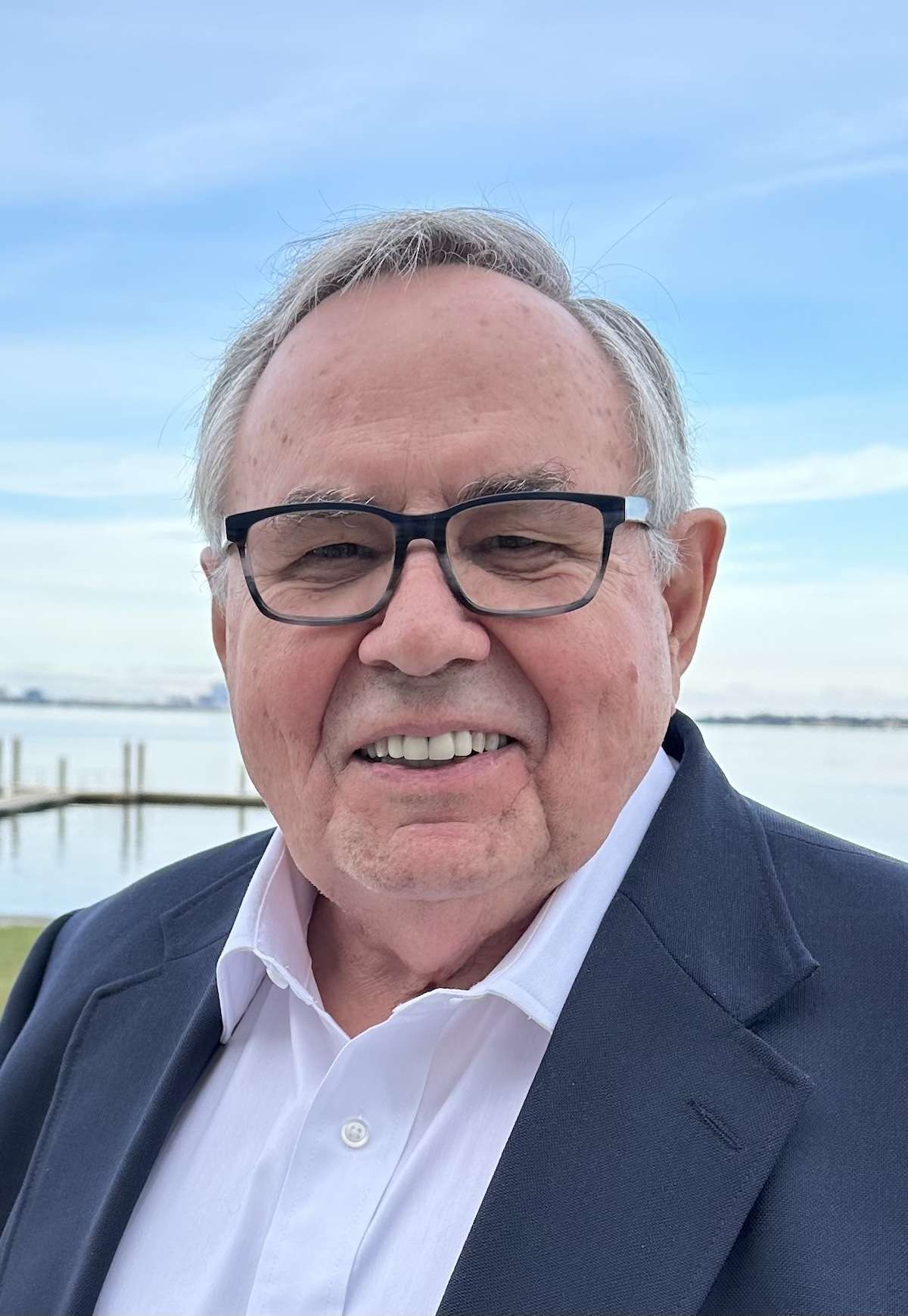 A man with glasses in a blue jacket with a white shirt.