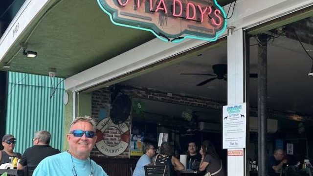 A man standing underneath an O'Maddy's sign.