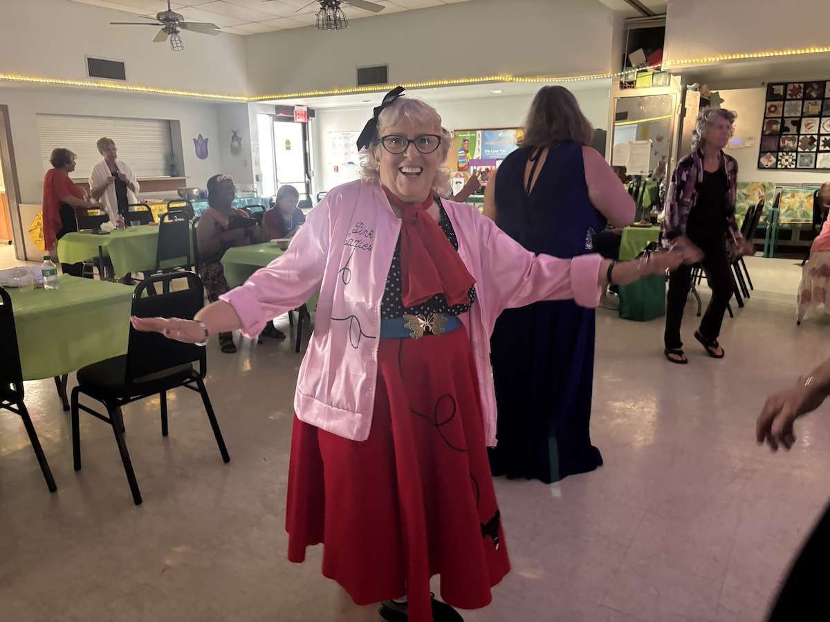 A woman in a pink ladies jacket dancing.