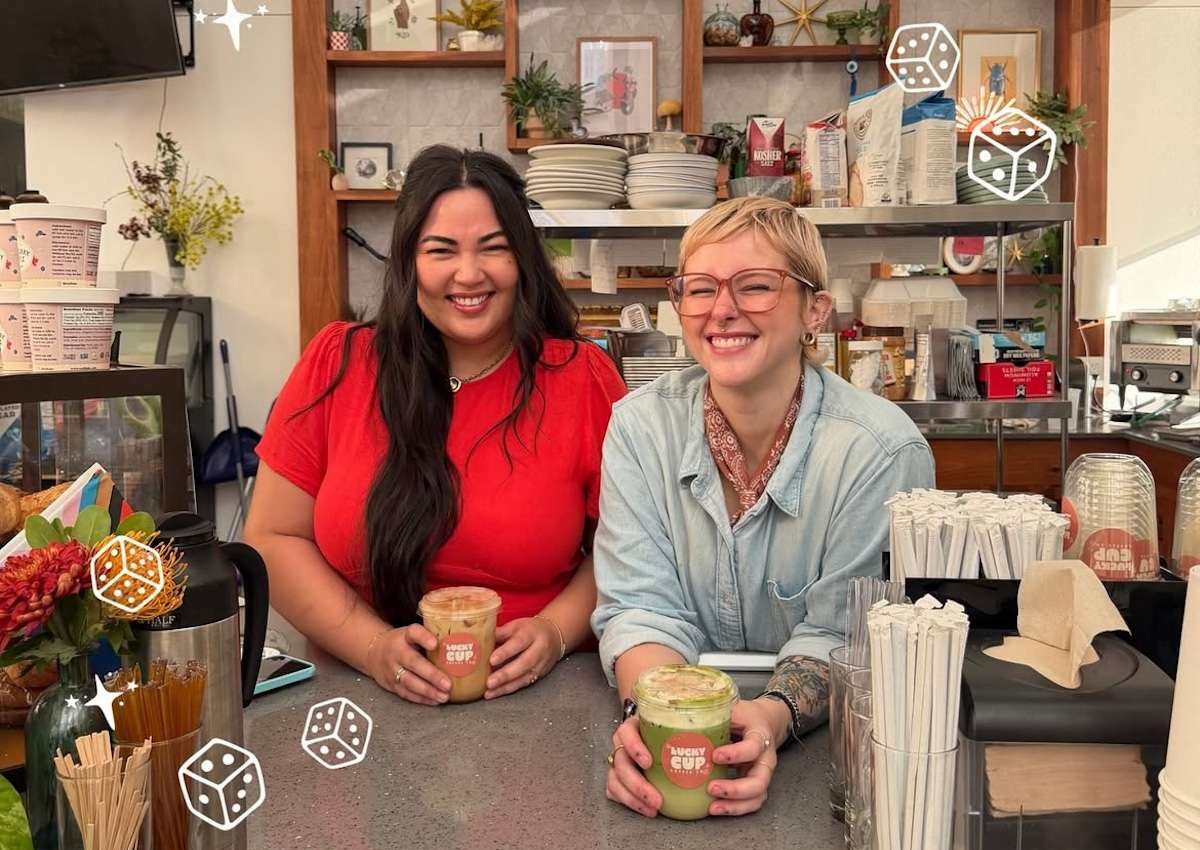 two people smiling behind a counter at a coffee shop.