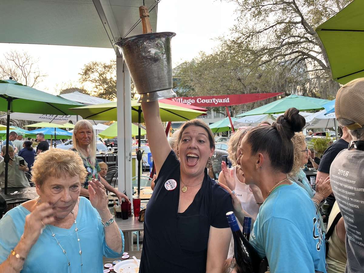 a woman holding up a bucket of champagne.