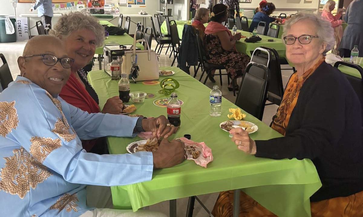 A table of men and women enjoying food.