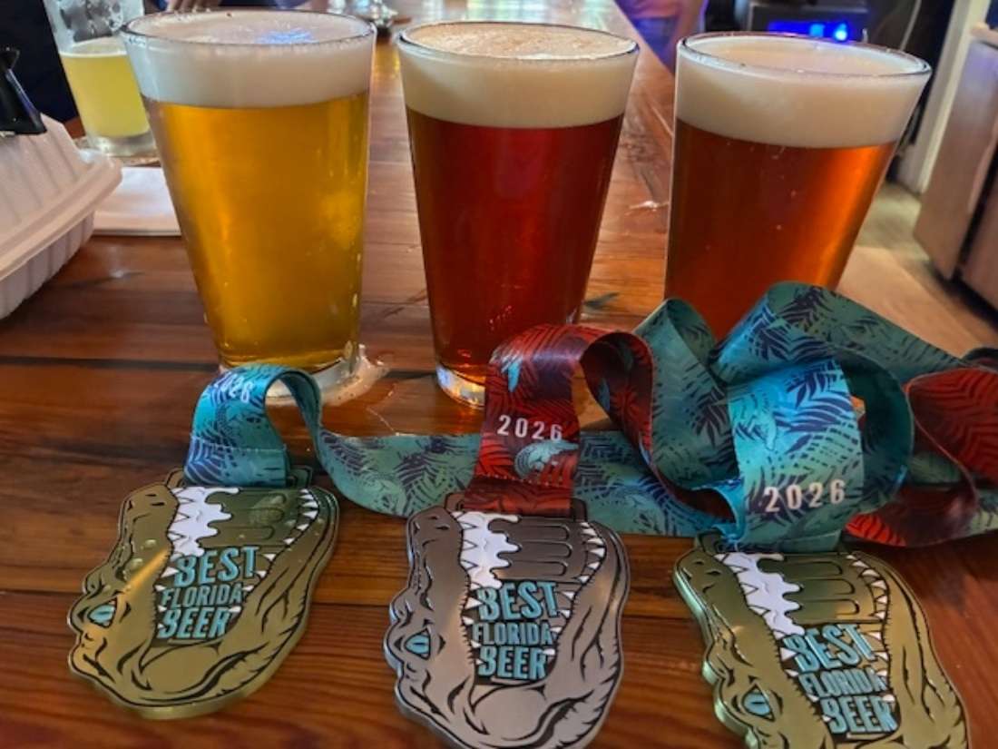 Three beers are laid out with the medals they earned