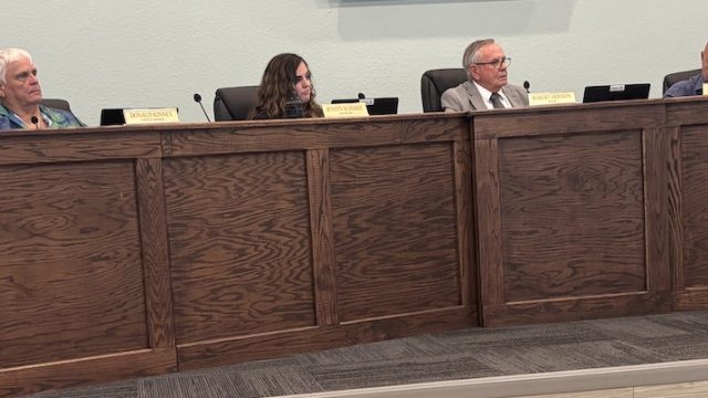 Six people sitting on the dais in city hall.