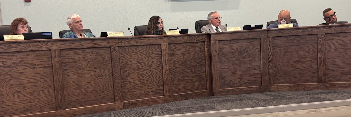 Six people sitting on the dais in city hall.