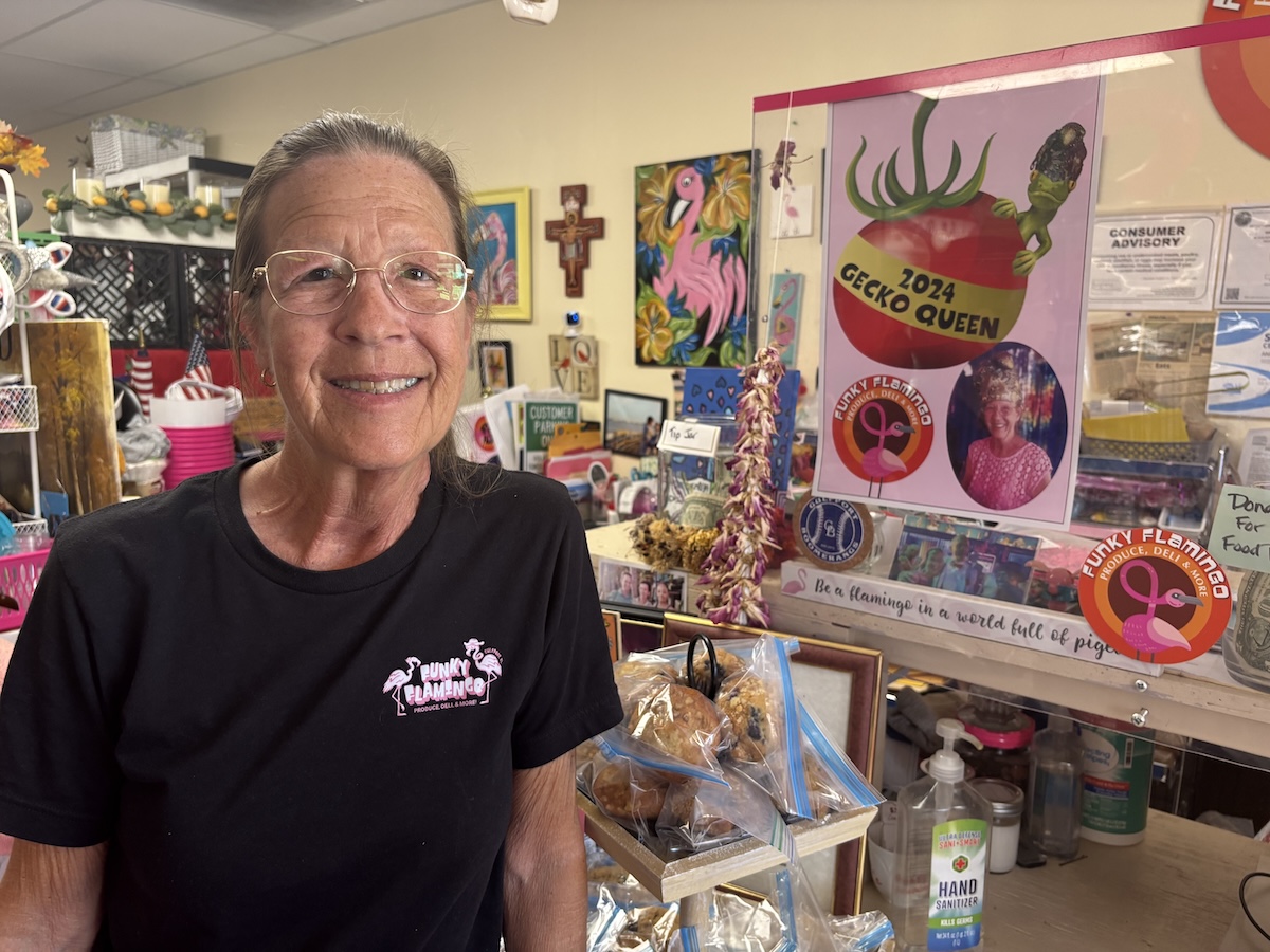 A woman smiling brightly while standing in a room packed with items.