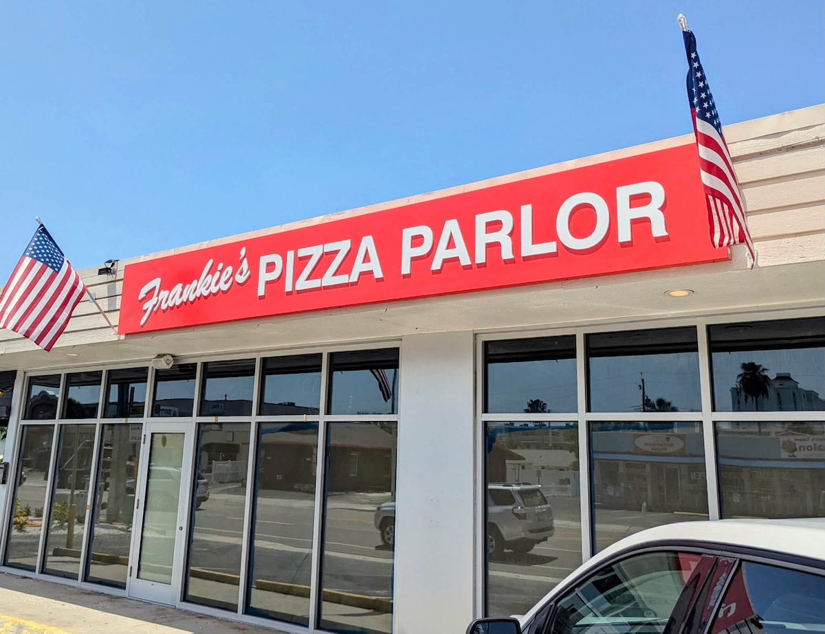 a storefront with a red sign that reads "Frankie's Pizza Parlor"