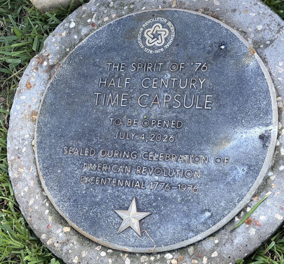 a metal circle with words that read "the Spirit of '76 half century time capsule to be opened jul y4, 2026, sealed during the celebration of american revolution bicentennial 1776-1976."