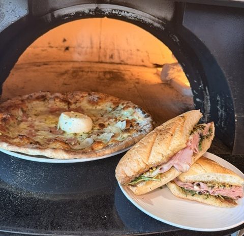 a pizza and a sandwich next to a grill.